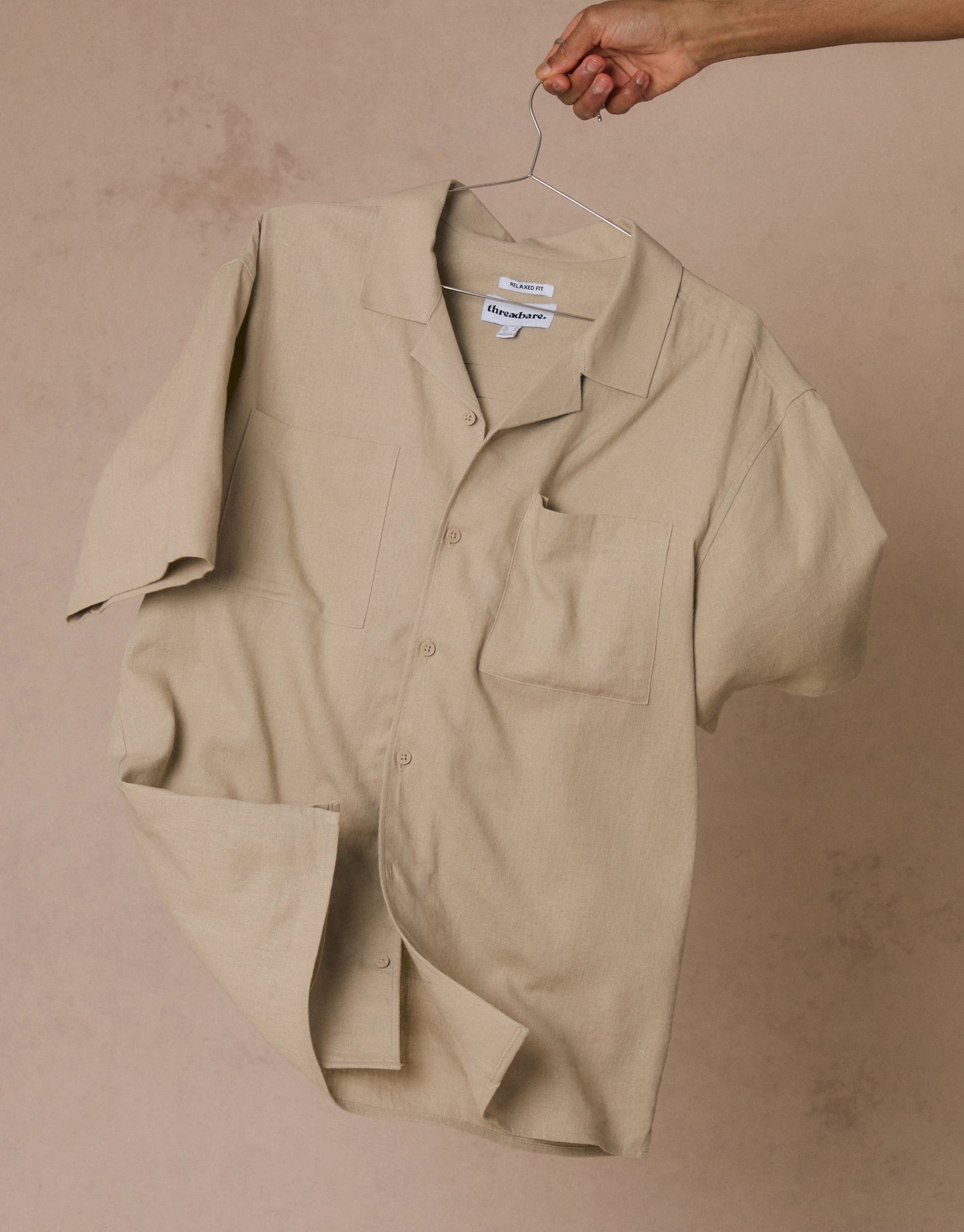 Man holding hanger containing a linen shirt