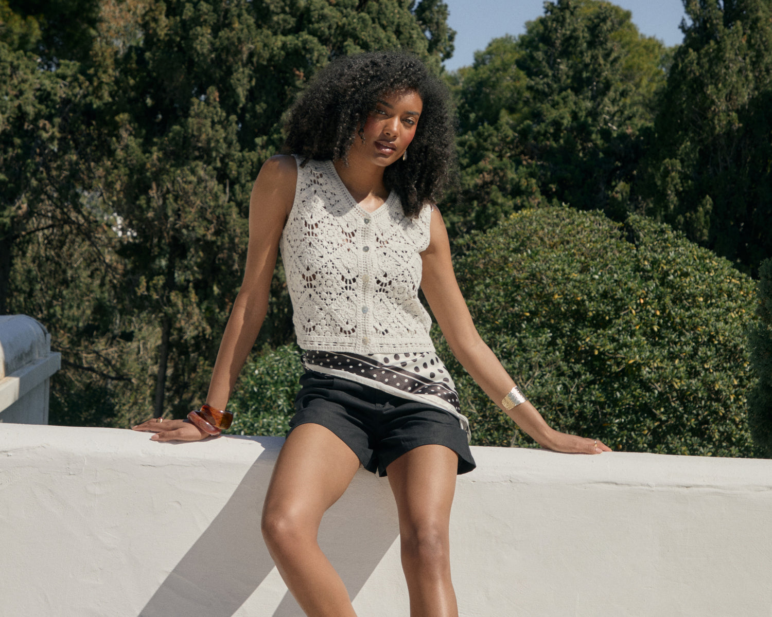 Threadbare Crochet Button Up Vest in White worn by woman sat on wall